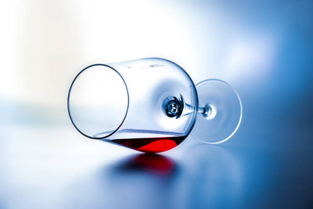 Fallen glass with the remnants of wine in it. White-blue background. Elegant style. Close-up.