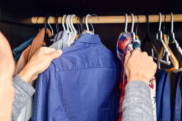 istock young man choosing a shirt from a clothes rack 1129825538
