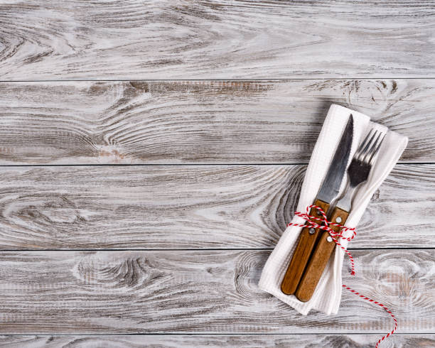 istock Empty wooden table background and fork and knife on napkin. Dinner, lunch or breackfast concept. 1129825951