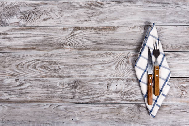 istock Empty wooden table background and fork and knife on napkin. Dinner, lunch or breackfast concept. 1129826792