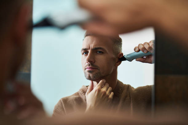 istock Handsome young man removing hair from ear at bathroom 1129826954