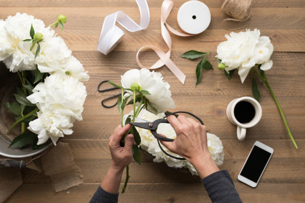 istock OVerhead of Floral Designer Assembling a Wedding Bouquet with smart phone 1129827347