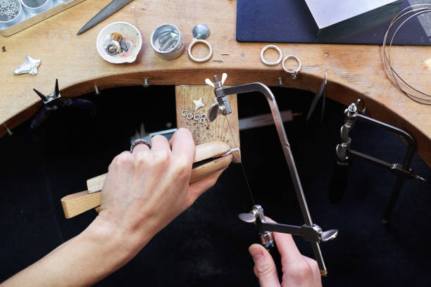 istock Jeweler at work in jewellery workshop, wonan hands making silver thing. tools set. 1129827565