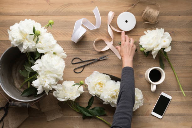 istock Woman's hand reaching for ribbon while arranging flowers 1129827570