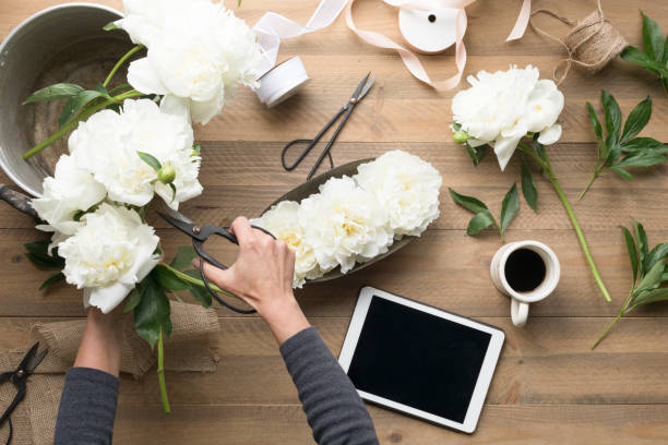 istock Women Hands Cutting Flowers with tablet and coffee 1129829419