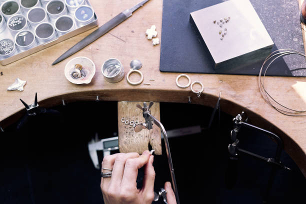 istock Jeweler at work in jewelery workshop, woman hands making silver thing. tools set. 1129830100