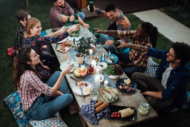 Friends toasting with wine and beer at rustic dinner party Friends toasting with wine and beer at rustic dinner party outdoor dining photos stock pictures, royalty-free photos & images