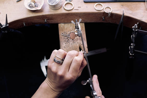 istock Jeweler at work in jewelery workshop, woman hands making silver thing. tools set. 1129831114