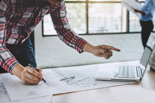 istock Construction concept of Engineer or architect meeting for project working with partner and engineering tools on model building and blueprint in working site 1129832728