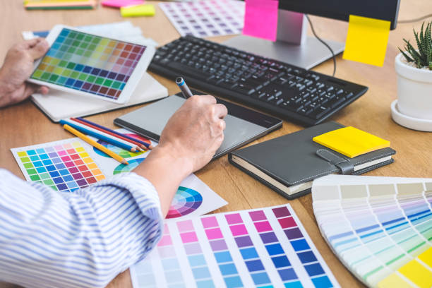 istock Image of male creative graphic designer working on color selection and drawing on graphics tablet at workplace with work tools and accessories in workspace 1129832782