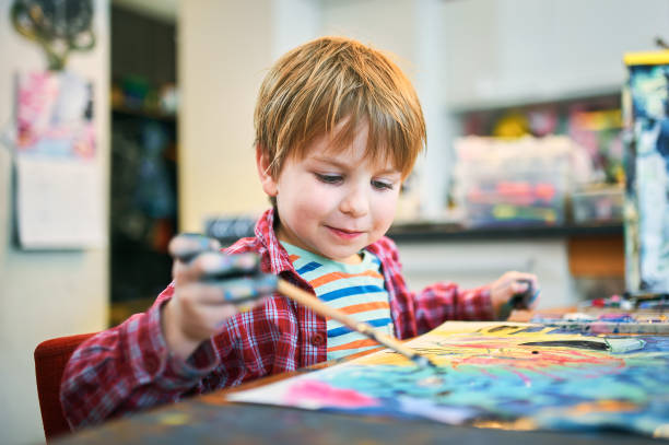 carino bambino felice, adorabile bambino in età prescolare, dipinto in uno studio d'arte soleggiato. giovane artista al lavoro - preschooler preschool child painting foto e immagini stock