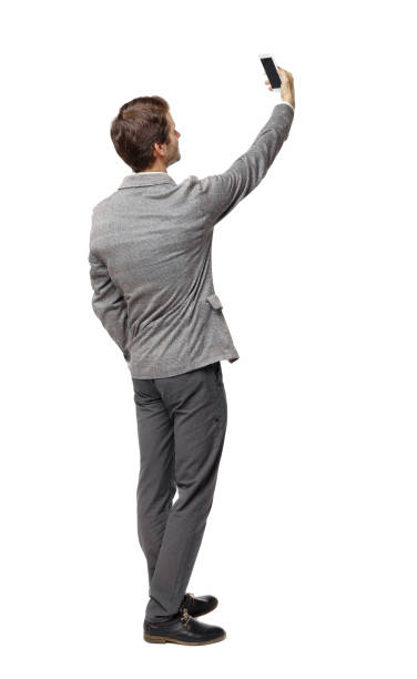 istock Back view of a businessman in a suit making a selfie. 1129835233