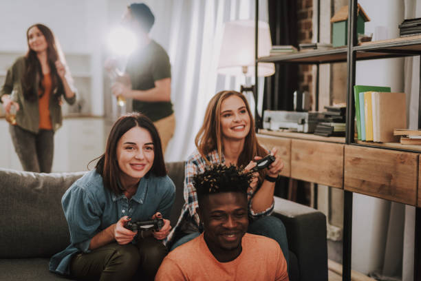 istock Cheerful girls holding joysticks while afro american guy smiling 1129840366