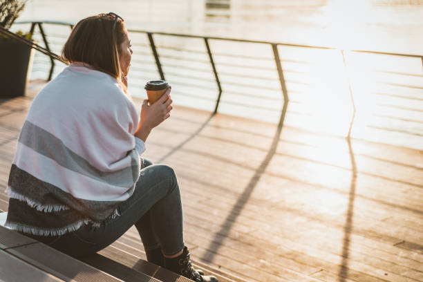 istock Sad woman standing by the water during sunset 1129841414