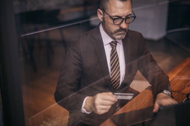 istock Senior businessman using laptop and credit card 1129843141