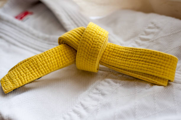 istock Yellow martial art belt on white judo, karate or aikido uniform 1129843348