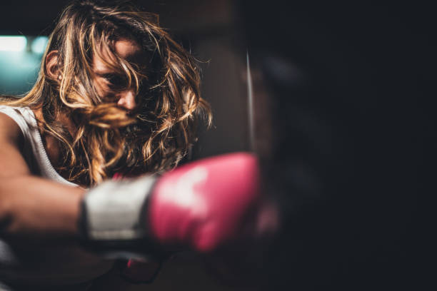 istock Young lady punching a punching bag 1129844417