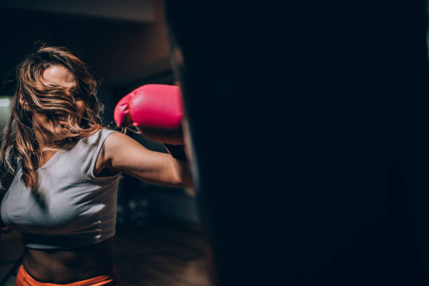 istock Lady boxer punching a punching bag 1129844423