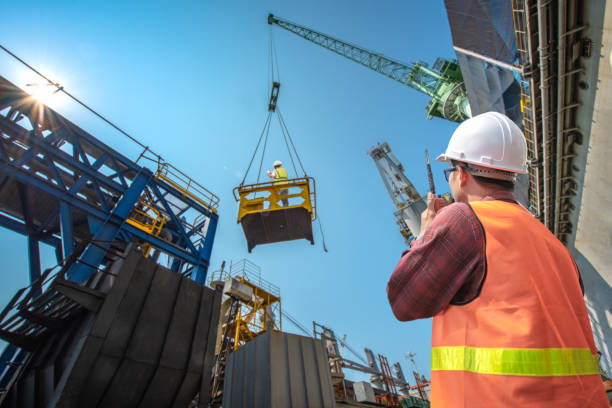 High level at risk engineering, loading master connecting to gantry crane driver by walkie talkie for lifting safety in loading the goods or shipment, lifting by gantry crane, working at risk on the high level insurance gantry crane stock pictures, royalty-free photos & images