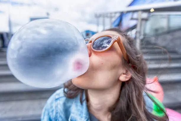 Photo of Woman portrait blowing a bubble chewing gum