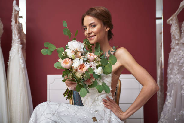 istock Smiling bride in wedding salon posing with flowers 1129854838
