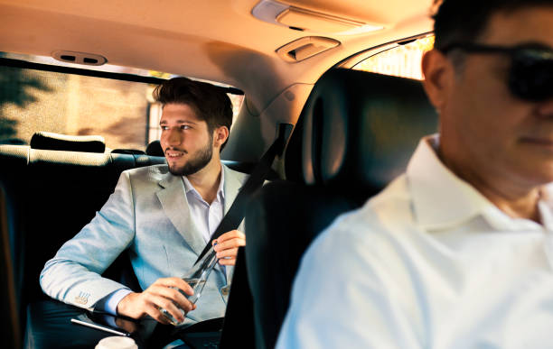istock Young businessman with his driver in a  car 1129860289