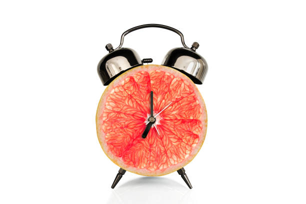 istock Grapefruit slice on alarm clock, isolated on white background, fruit and vitamins diet at breakfast nutrition concept 1129860502