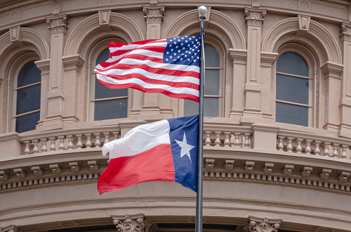 The US flag and Texas state flag flying at The Texas Capitol building in Austin