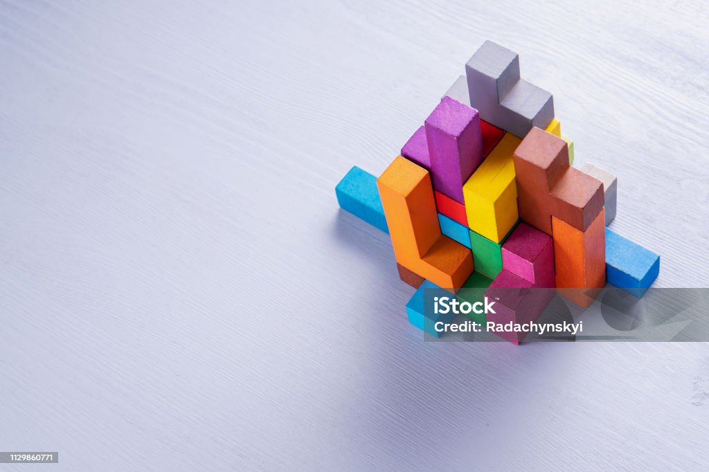 Abstract construction from wooden blocks. Colorful wooden building blocks. Abstract construction from wooden blocks shapes with copy space. The concept of logical thinking, geometric shapes. Colorful wooden building blocks Contemplation Stock Photo