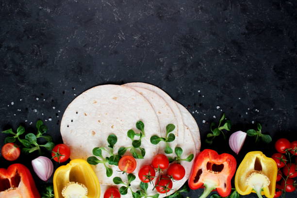 Tortillas flat various vegetables for tacos or burrito making on dark background. stock photo