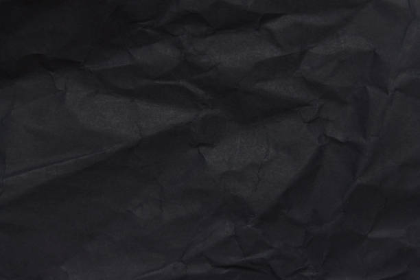 Dark black crumpled paper close up texture background
