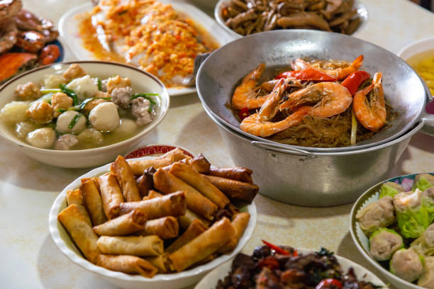 istock Casseroled prawns with Glass Noodels in Small Iron Pan with Fish, Fried Spring Rolls, Dim Sum, Seafood, Roasted Duck and Meatball Background on the Table. 1129866050