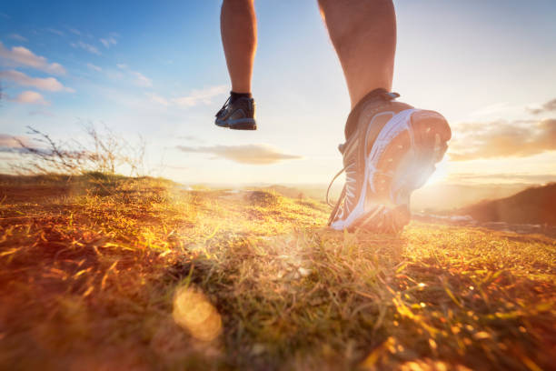 Cross-country running in early morning sunrise Outdoor cross-country running in morning sunrise concept for exercising, fitness and healthy lifestyle feet pics stock pictures, royalty-free photos & images