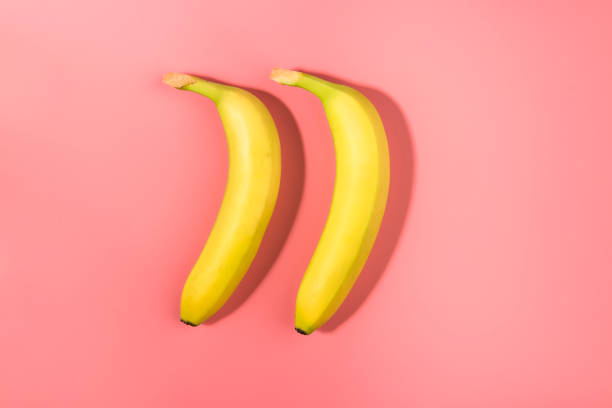 istock Two bananas on a pink background with contrast shadow 1129873076
