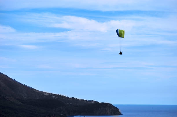 istock parachutist flying above the ocean and mountains 1129873262