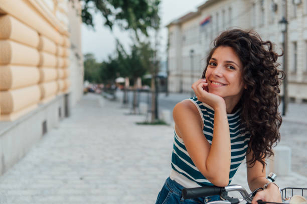 istock Smiling woman leaning on bicycle 1129874375