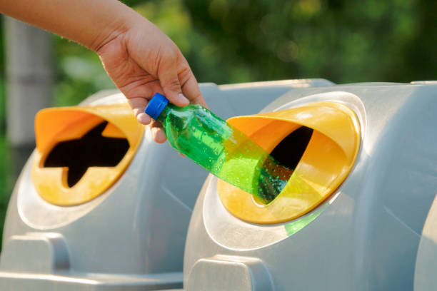 istock Hand holding recyclable plastic bottle in garbage bin with sunset light 1129878666
