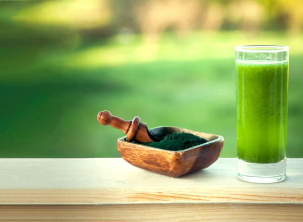 grüner smoothie mit spirulina auf holzhintergrund - barley grass juice green stock-fotos und bilder