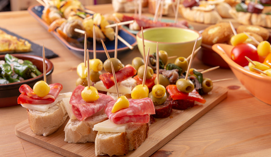Open sandwiches with salami, pepper, cheese and olives. Mediterranean tapas snacks.