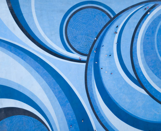 Aerial Drone View of People walking over a Circular Swirl Patterned Blue Floor stock photo