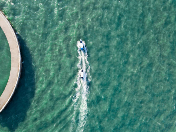 istock Two speed boats in a turquoise ocean passing a harbour wall 1129892792