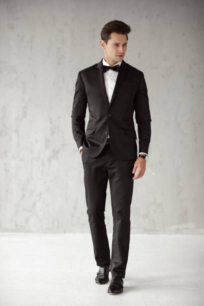istock Handsome man in black suit isolated on gray background 1129895504