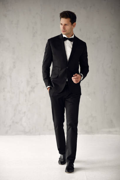 istock Handsome man in black suit isolated on gray background 1129895678