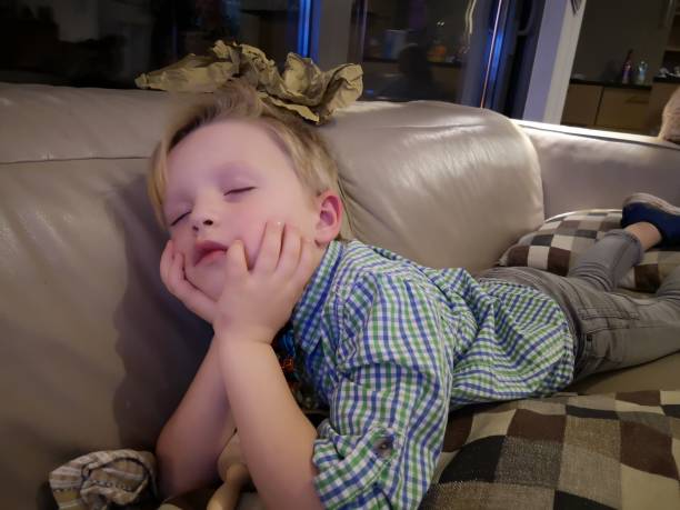 5 year old boy has fallen asleep in the couch stock photo
