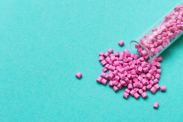 istock Plastic pellets. Pink Plastic granules from the tube on a turquoise background. Plastic Raw material . 1129899898