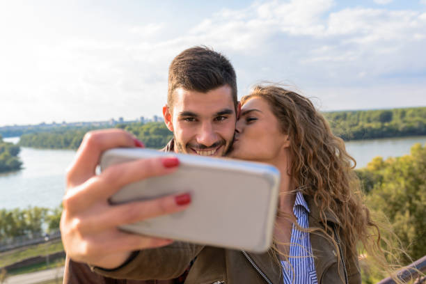 Happy young couple taking selfie photos near the river stock photo