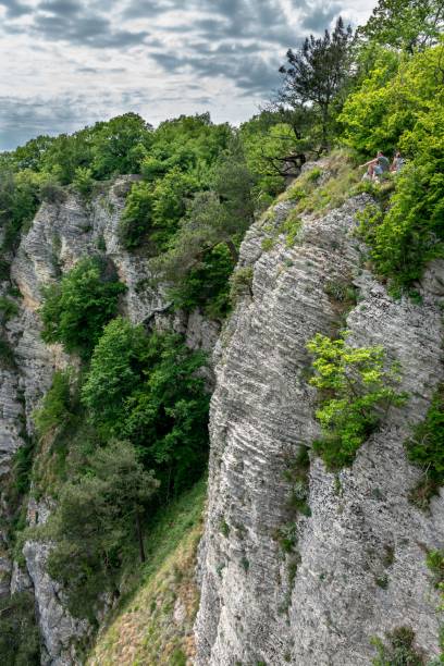 istock Mountain with a steep rocky slope. Several people are extremely sitting on the cliffs. 1129902840