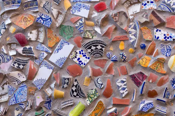 Colorful shards of ornamental floral traditional ceramic, reused after breaking for a wall outdoors. Safi, Morocco.