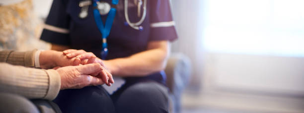A female nurse consoles a senior patient at home