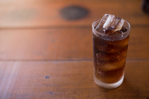 Soda with ice on brown wood with sunset light.